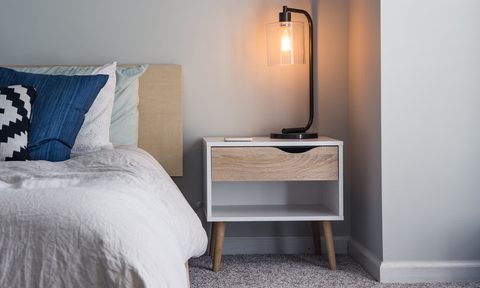 tall curved lamp on light wood bedside table
