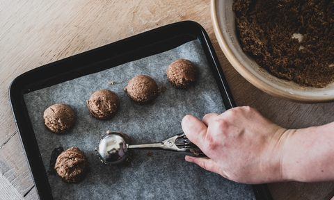 Person scooping cookie dough onto a tray