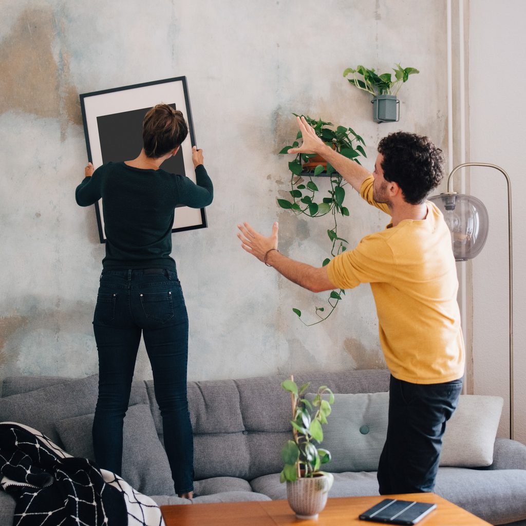 Two people hanging a picture on a wall