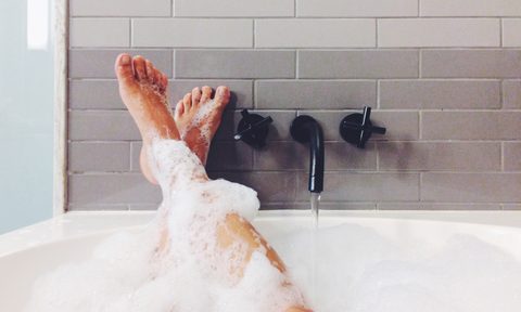 Person's legs in bathtub covered with bubbles
