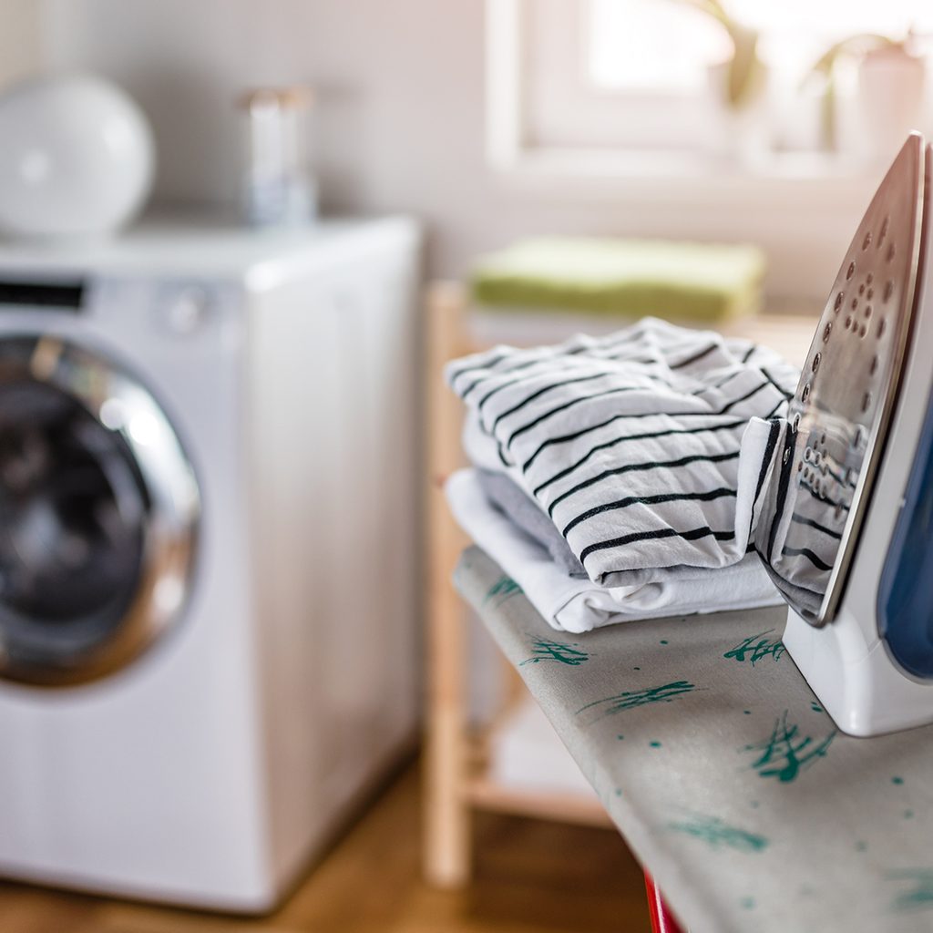 Iron and clothes on an ironing board in a laundry room