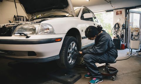 best mechanic seats creeper side view of female examining car wheel at auto repair shop