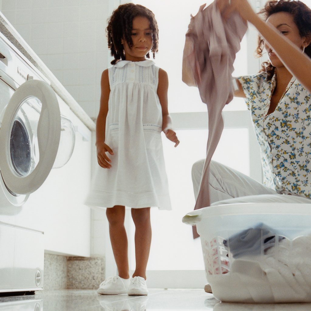 Mom and child placing laundry into a front loading washing machine