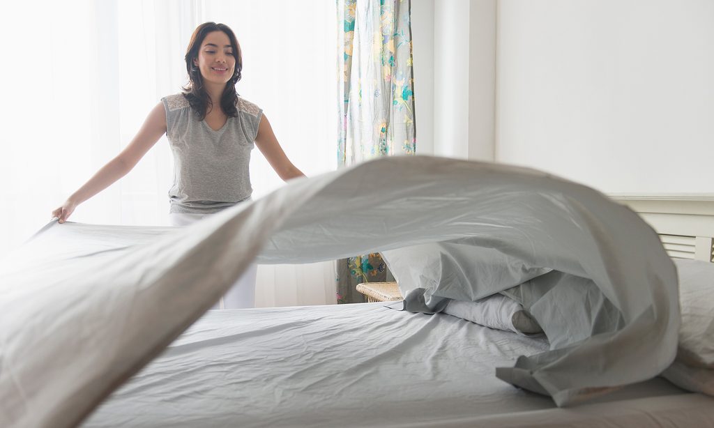 woman laying sheet flat on bed