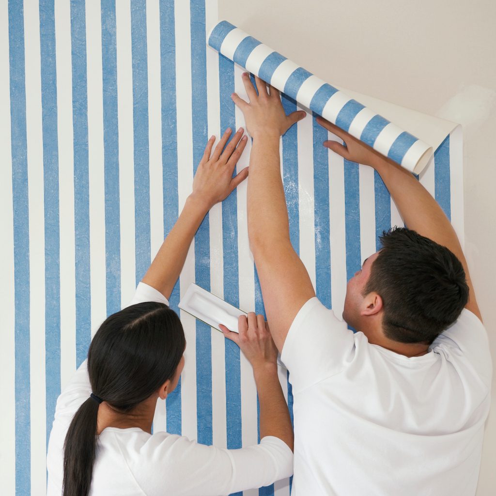 Couple putting up wallpaper