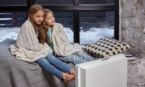 two girls warming up near heater
