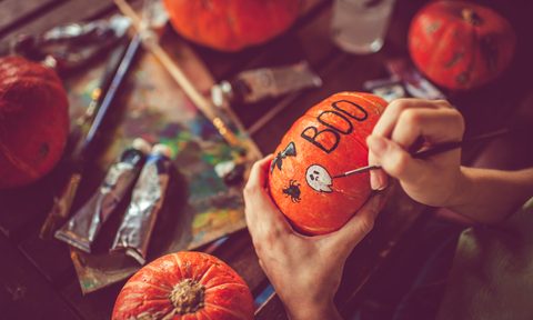 Young girl painting on pumpkin in Halloween