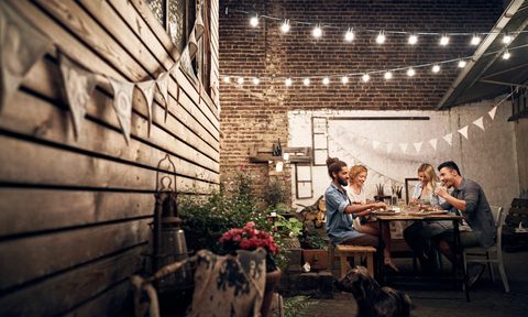 transfrom backyard simple touches patio lights deck gardening friends having a barbecue in the  eating together