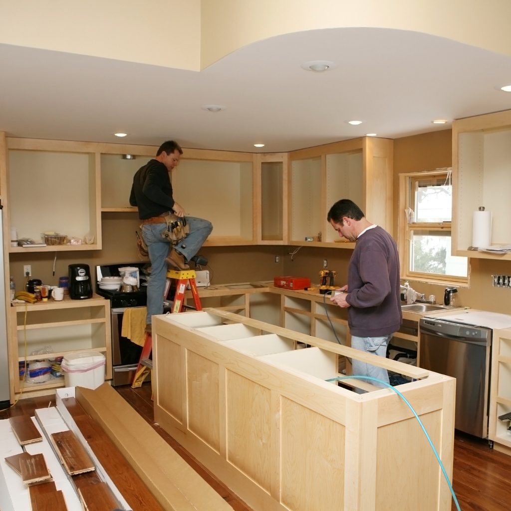 two people installing kitchen cabinets