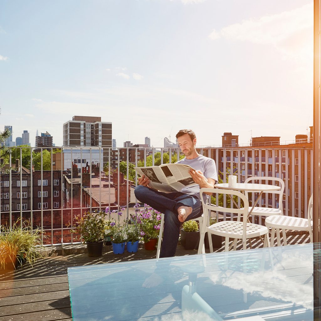 Reading the paper on an apartment deck