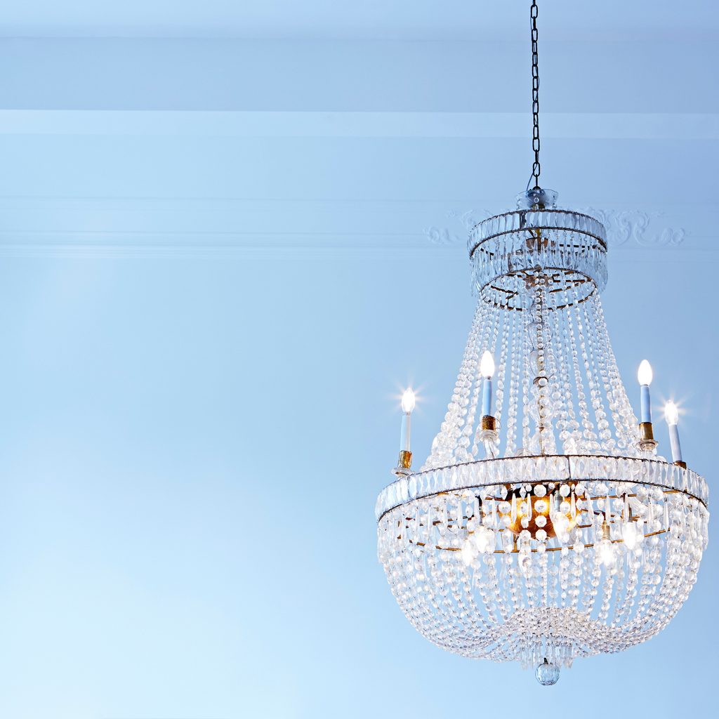 crystal chandelier hanging with blue wall behind it
