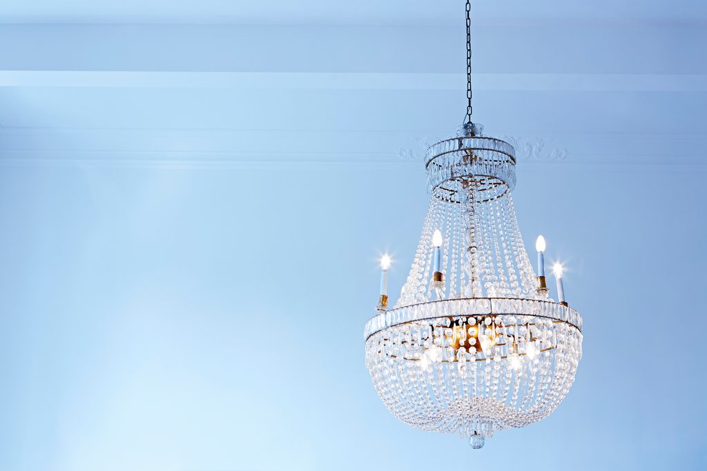 crystal chandelier hanging with blue wall behind it