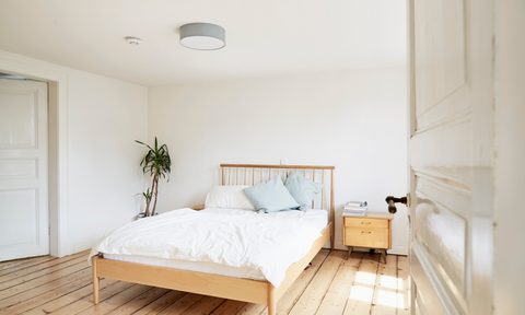 Bright modern bedroom with wood floor and white linens