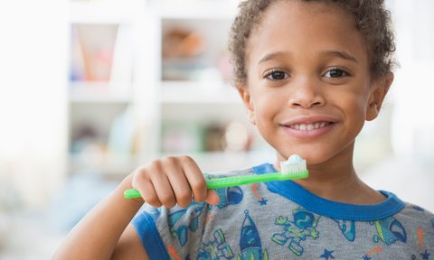 the best kids toothpaste with and without fluoride mixed race boy brushing his teeth