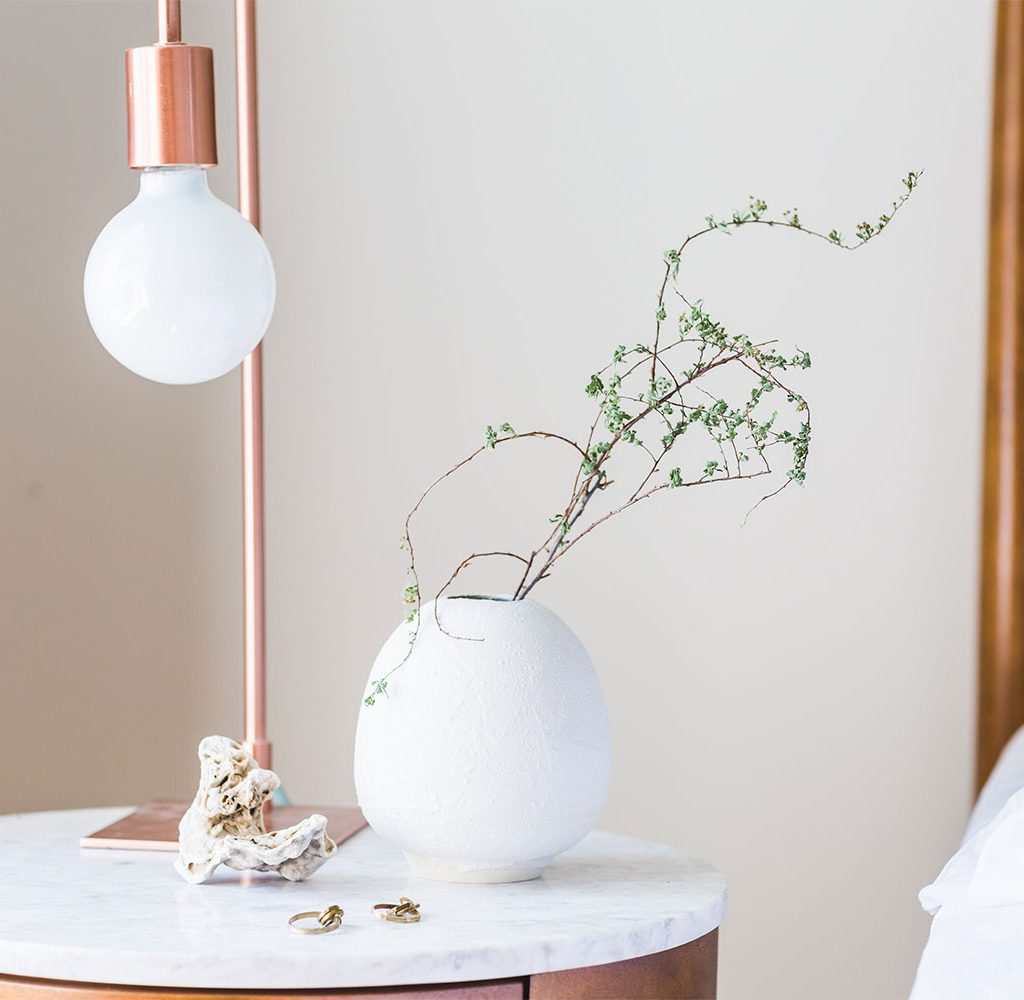 clean bedside table with plants and lamp