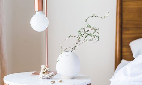 Clean bedside table with plants and lamp