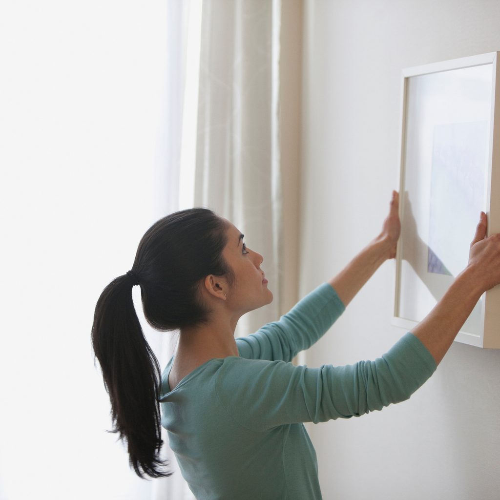 Woman hanging a frame on the wall