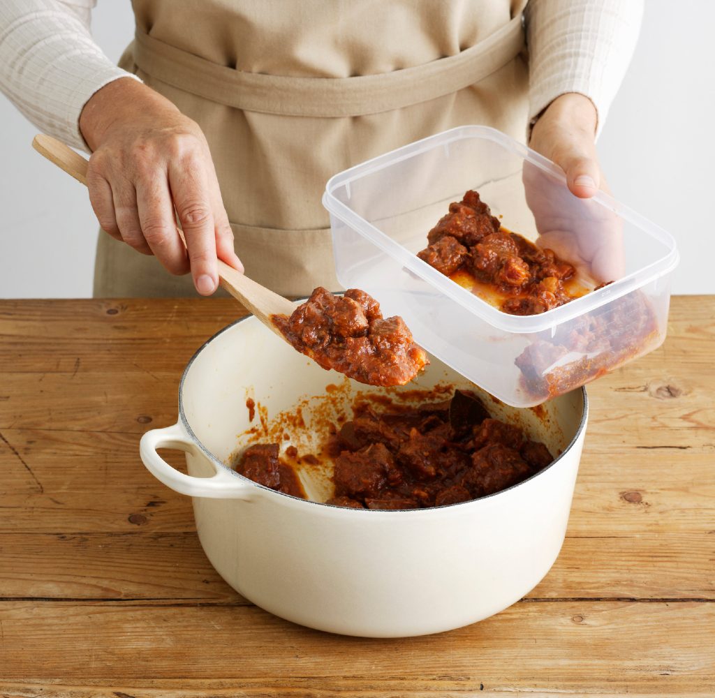 person putting leftovers into storage container