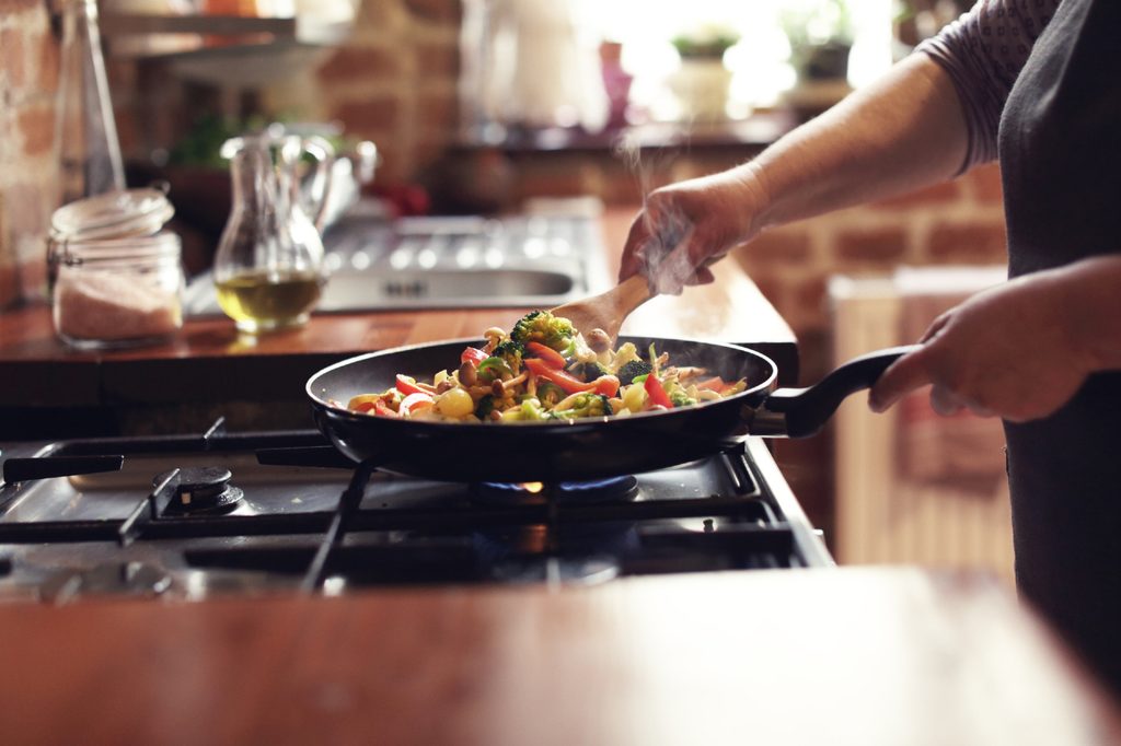 person cooking stir fry on stovetop