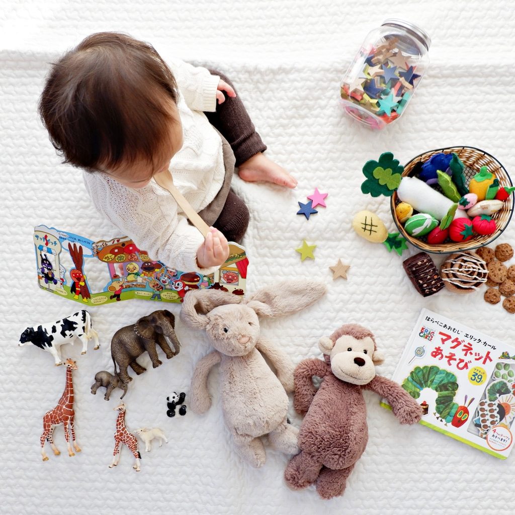 baby surrounded by various toys