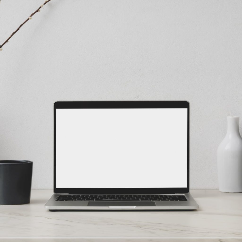 Laptop on desk with white wall