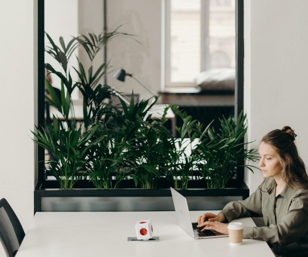 Woman working at desk with mirror and plants