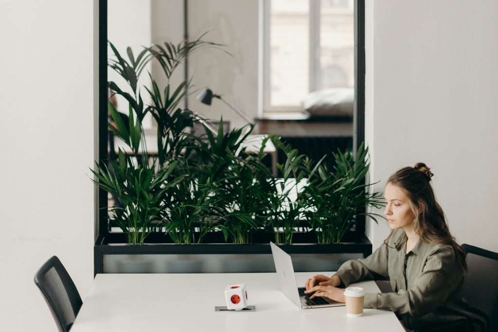 Woman working at desk with mirror and plants