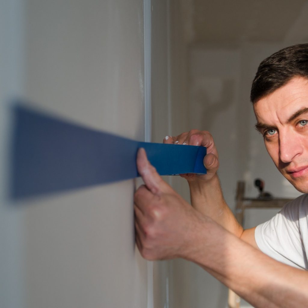 Man using blue painter's tape on wall