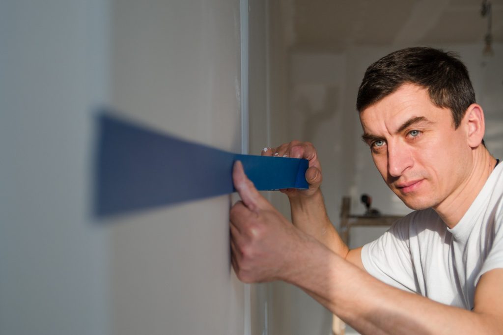 Man using blue painter's tape on wall