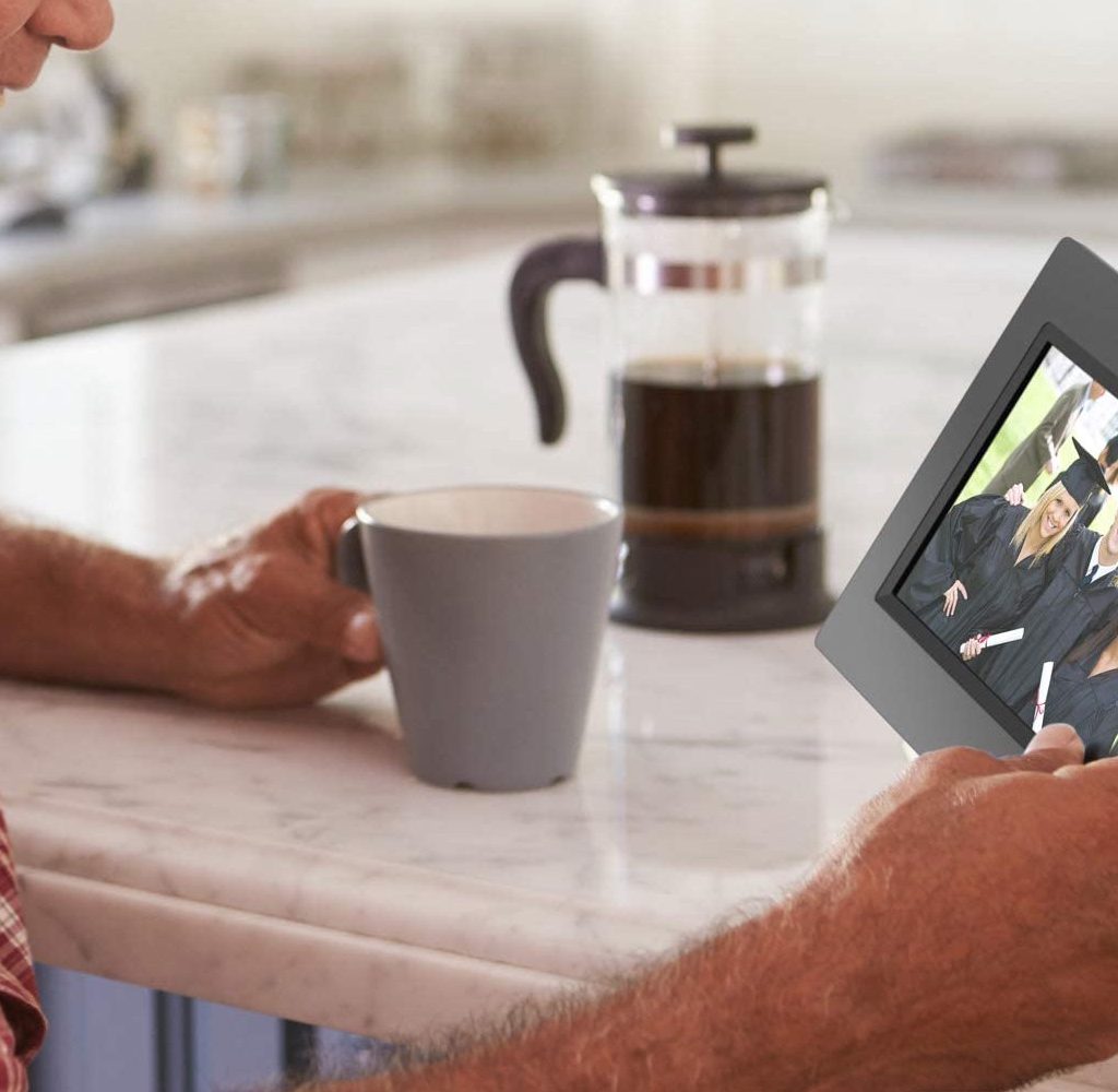 Man dirinking coffee and looking a digital photo frame