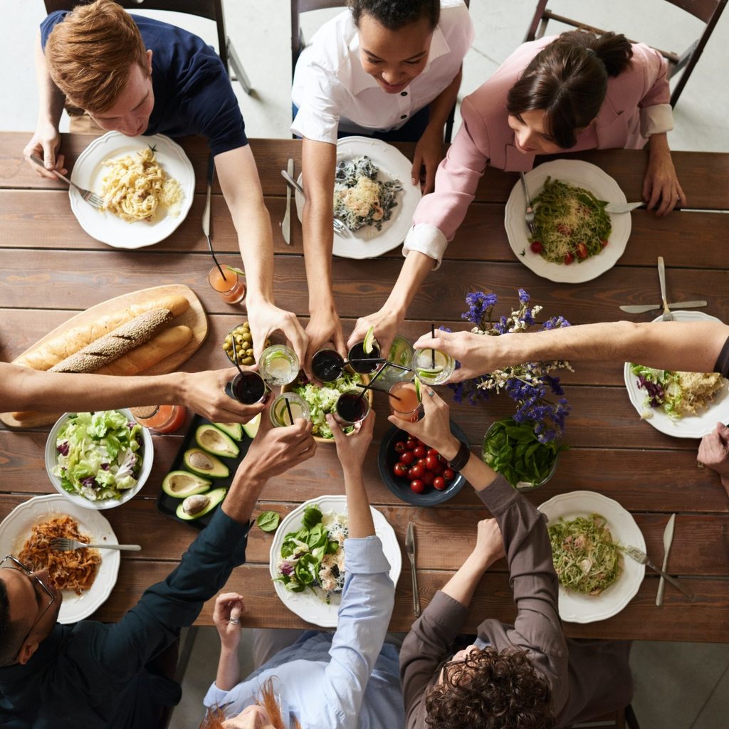 Friends sitting at wooden table eating dinner