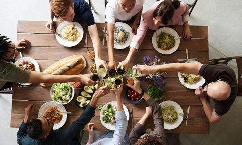 Friends sitting at wooden table eating dinner