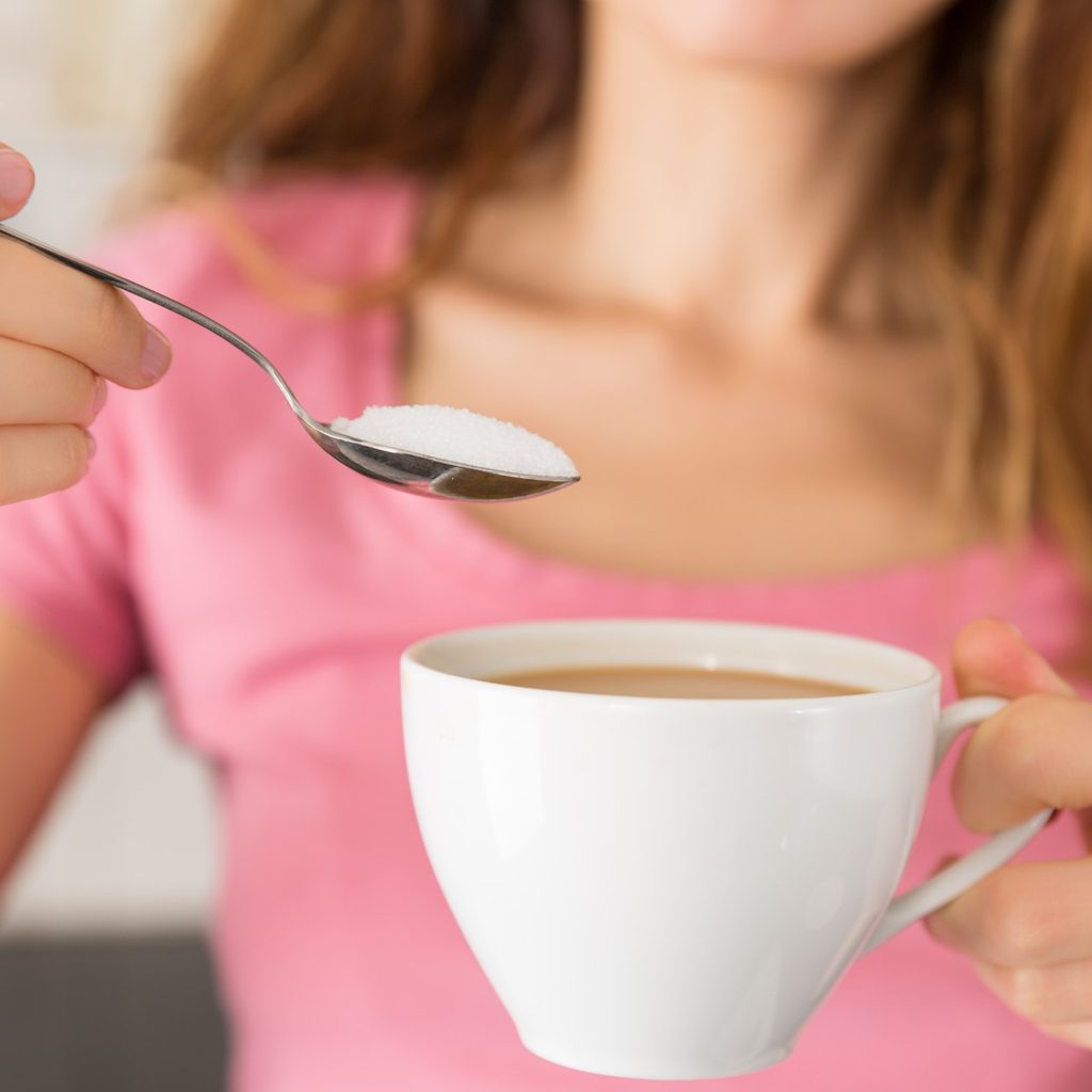 Woman with coffee and spoonful of sugar