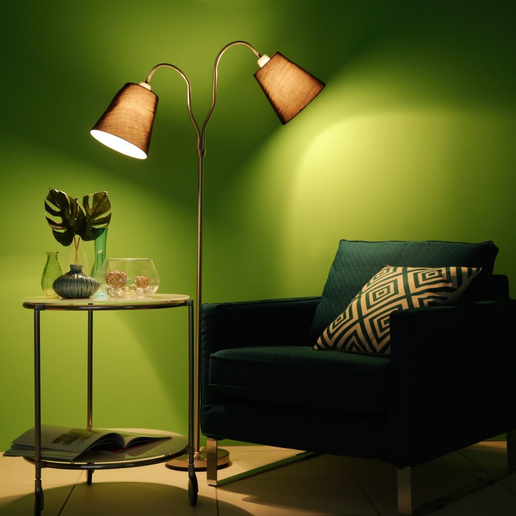 Green chair in room with green walls and lamp