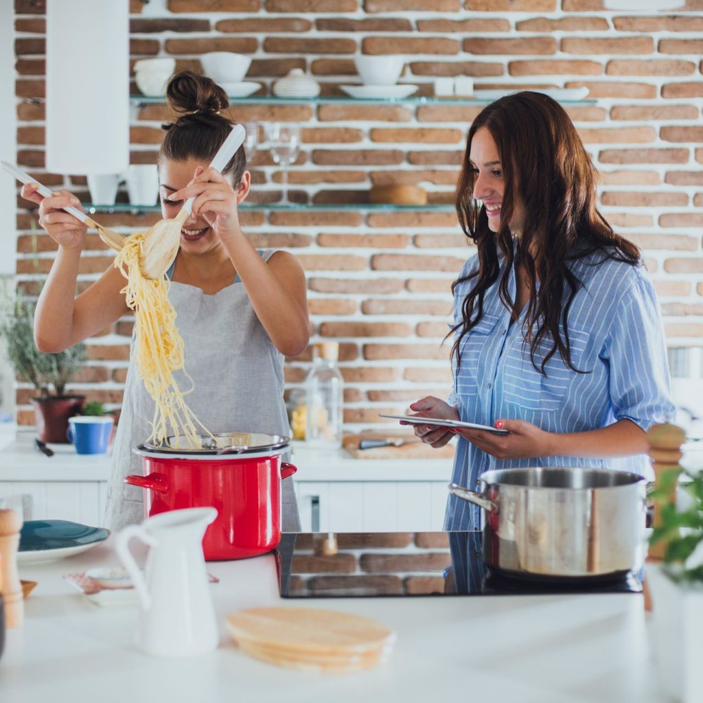 two women cooking together in kitchen