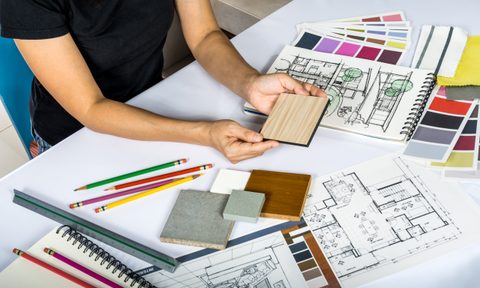Person sitting at design table with different drawings and color choices
