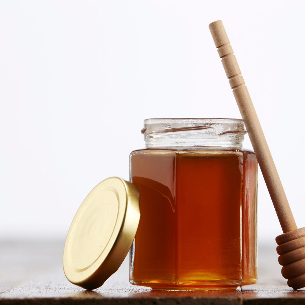 Jar of honey with a serving stick
