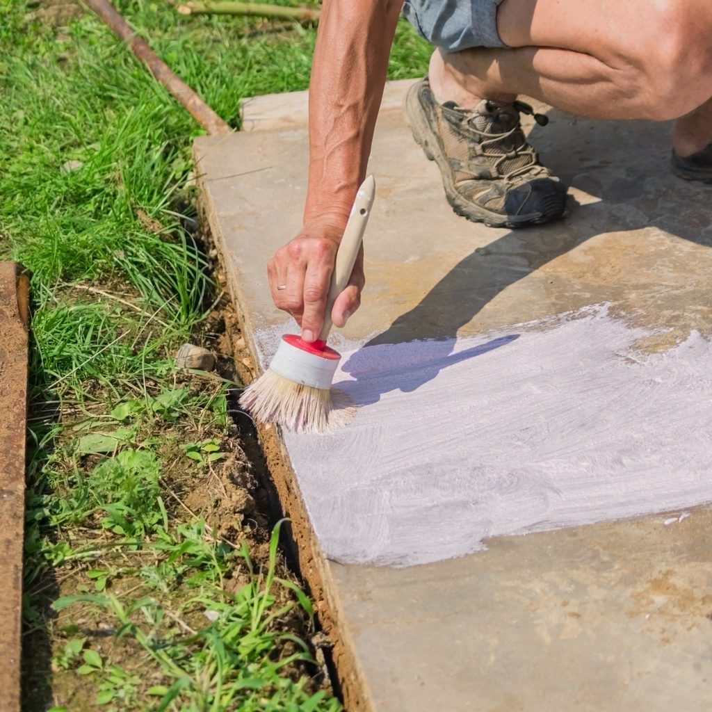 Person painting a concrete patio