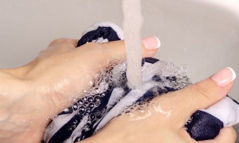 Female hands washing fabric under faucet