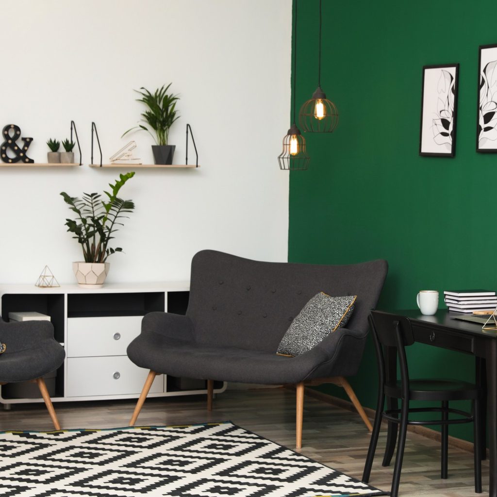 Clean living room with green wall, rug, and sofa