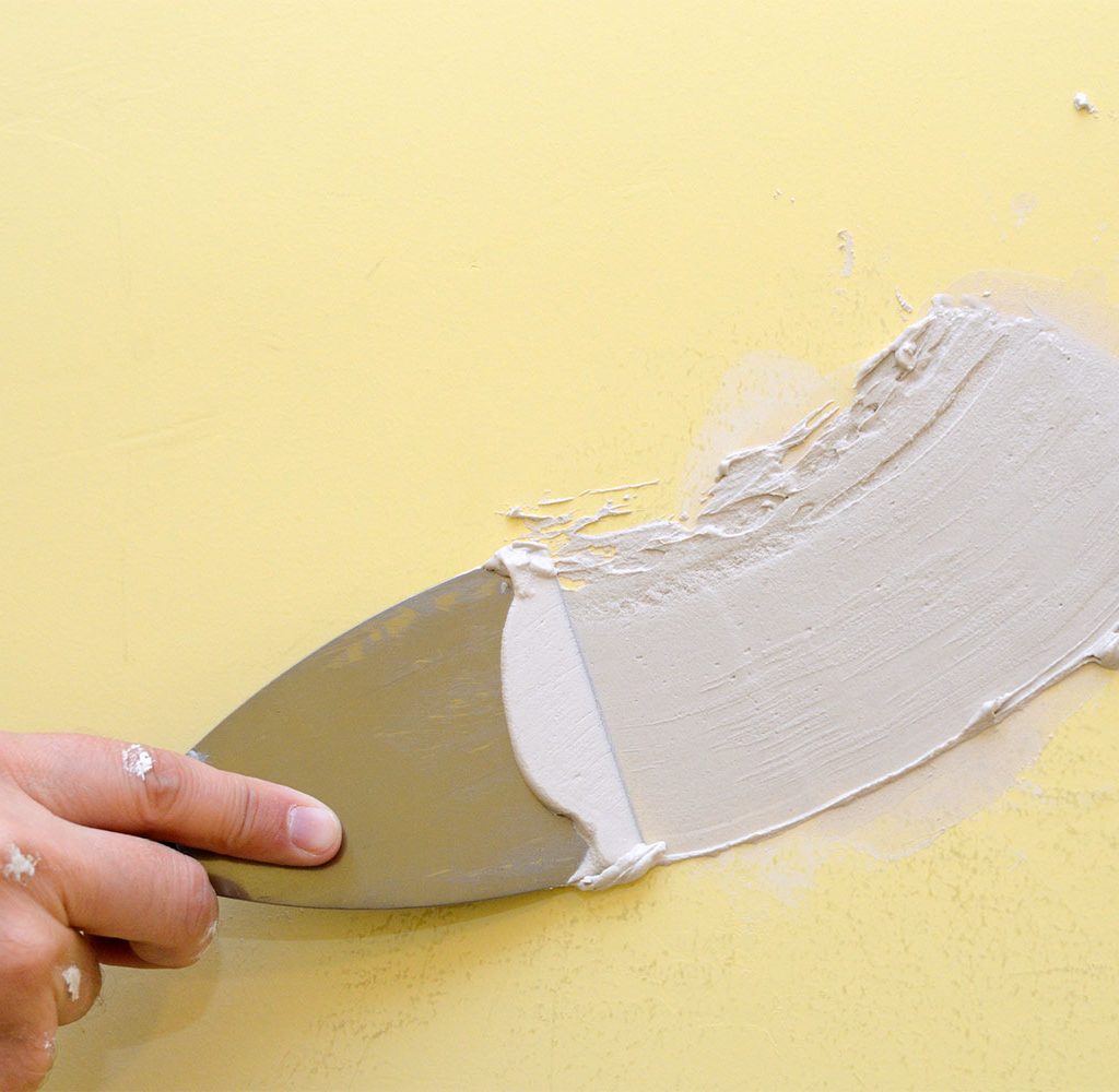 Person spackling yellow wall