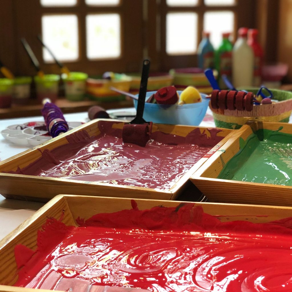 Three paint trayswith paint colors of red, green, and burgundy in them