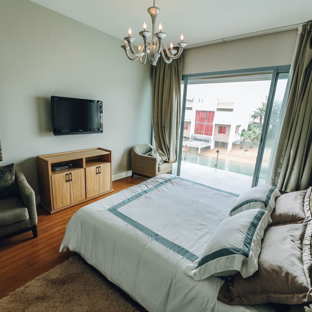 Well-made bed with pillows and nearby mirror