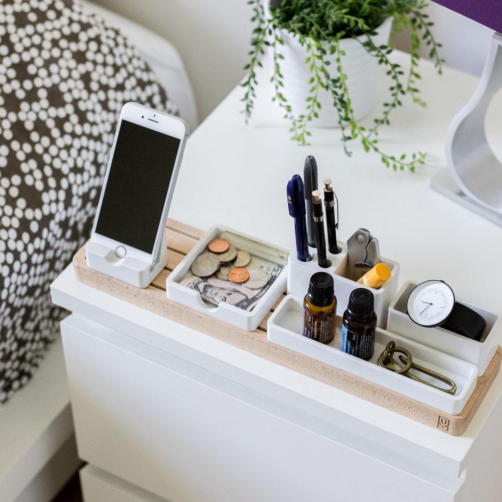 white cabinet with phone and makeup on top next to bed