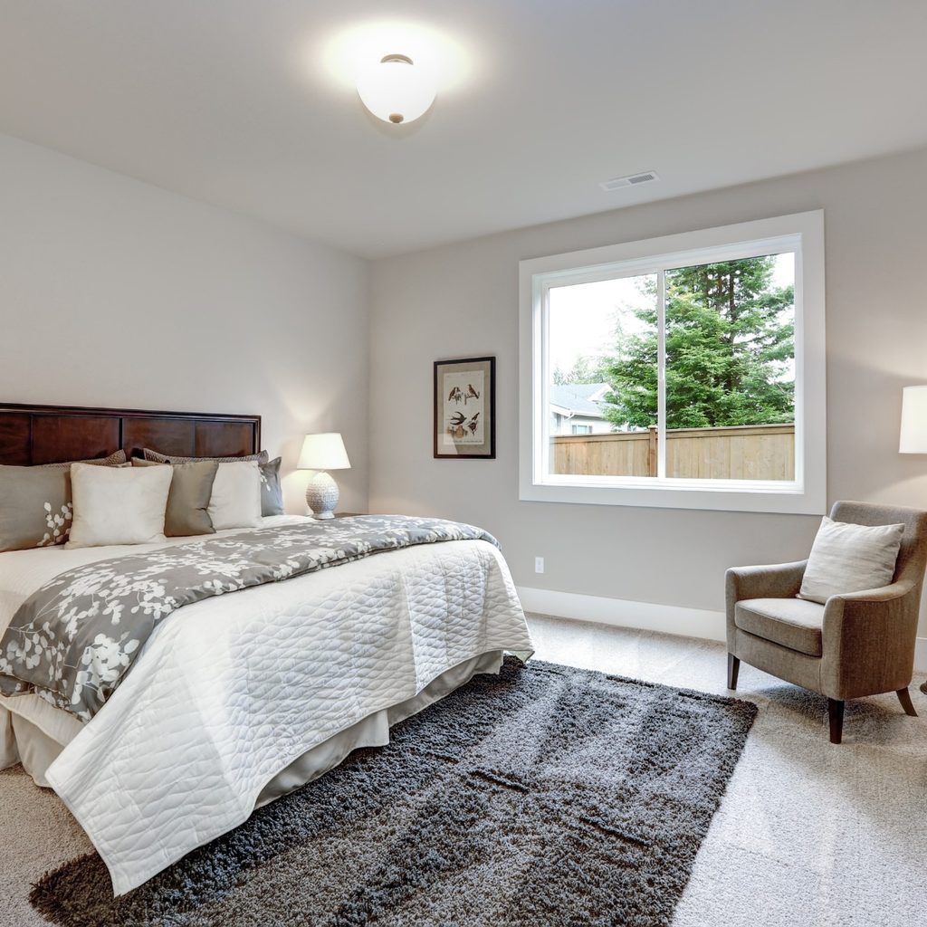 Bedroom with gray rug, bed, and chair