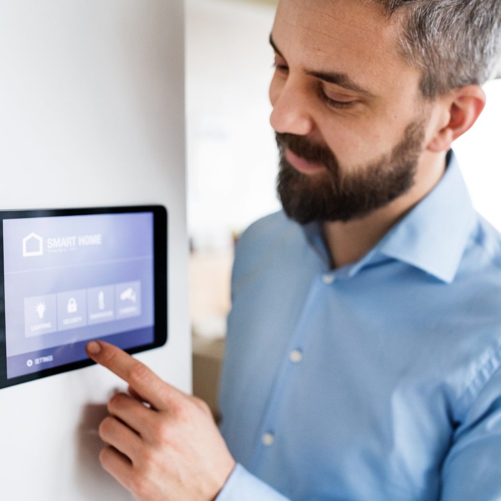 Man setting a smart thermostat in his home