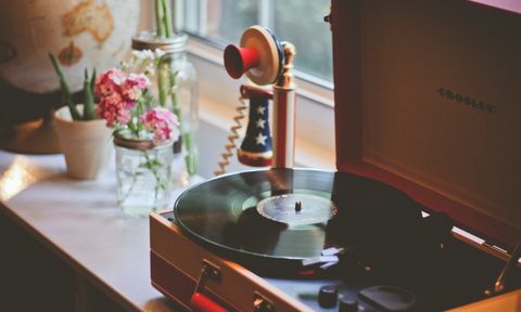 A record player sits on a windowsill next to a retro telephone