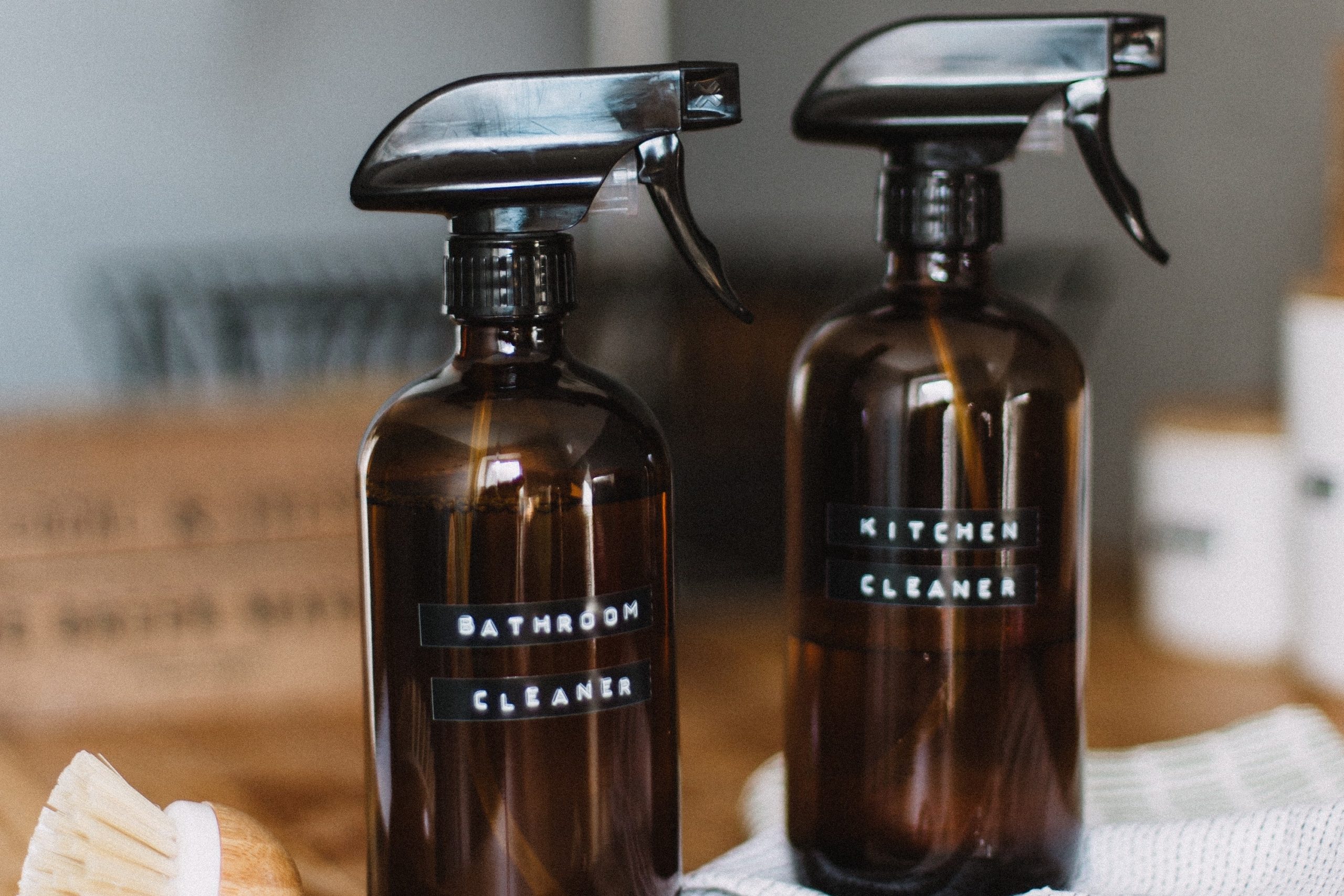 Two cleaning bottles sit on top of a wooden counter.