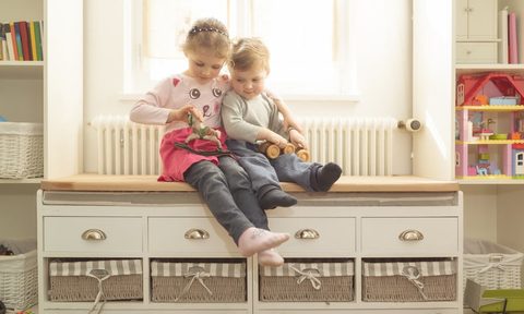 Two children sitting on indoor storage bench
