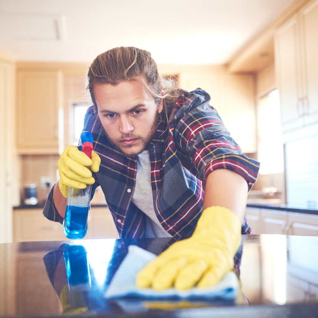 Man cleaning counter with spray bottle